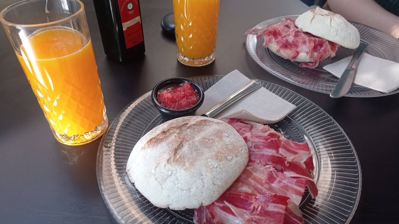 Molletes con jamón, tomate y zumo de naranja en una mesa de Bahía